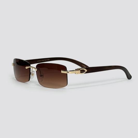 Sunglasses with gold frame and brown lenses on a light gray background