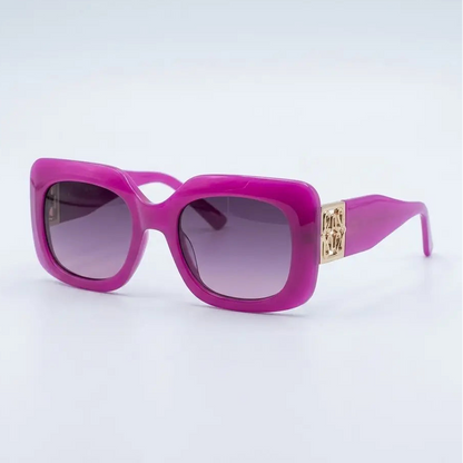 Bright pink square sunglasses with gradient purple lenses and a gold-tone metal logo plate on the temple arm, set against a clean white background.