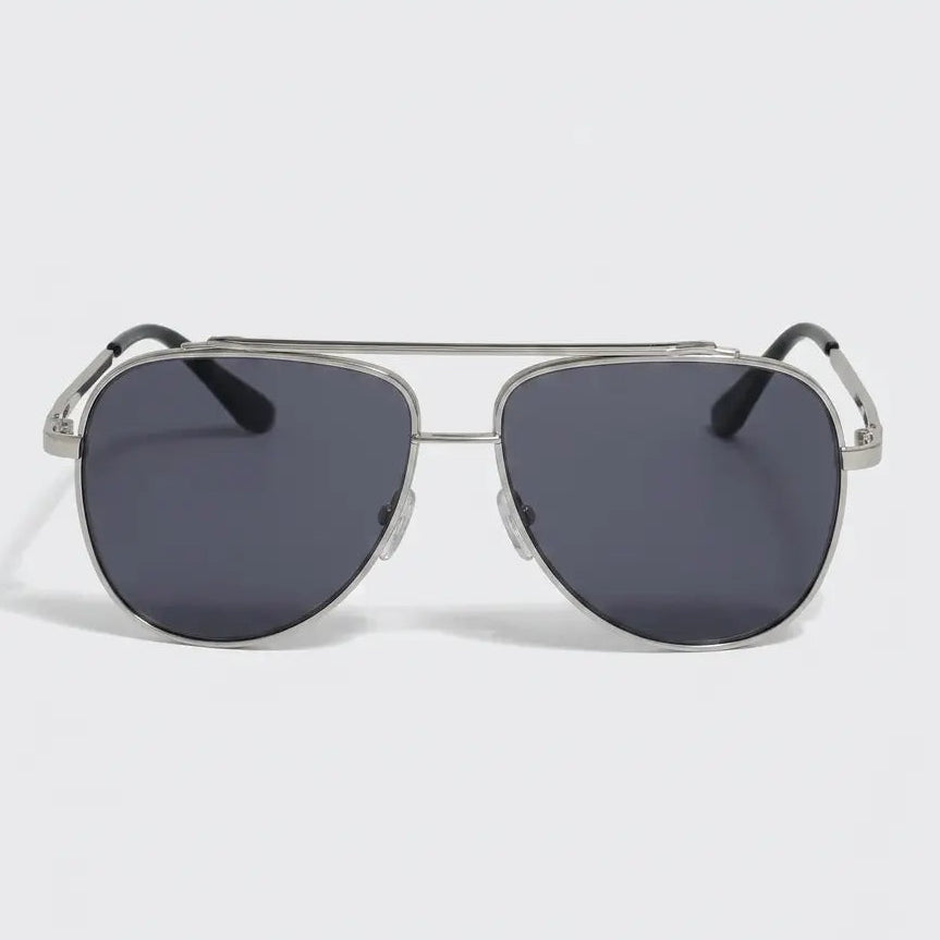 Aviator-style sunglasses with a silver metal frame, dark gray lenses, and black temple tips displayed on a light gray background.