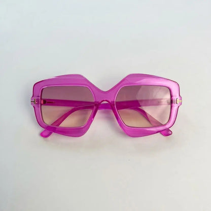 A pair of oversized square sunglasses with a translucent bright pink frame and pink-tinted lenses, photographed on a plain light background.