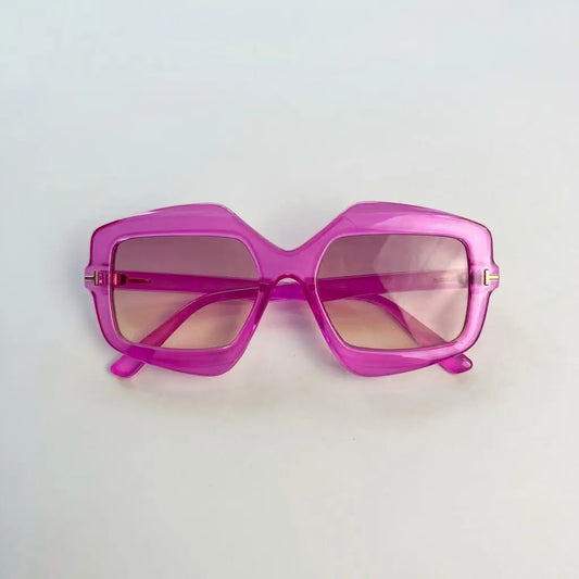 A pair of oversized square sunglasses with a translucent bright pink frame and pink-tinted lenses, photographed on a plain light background.