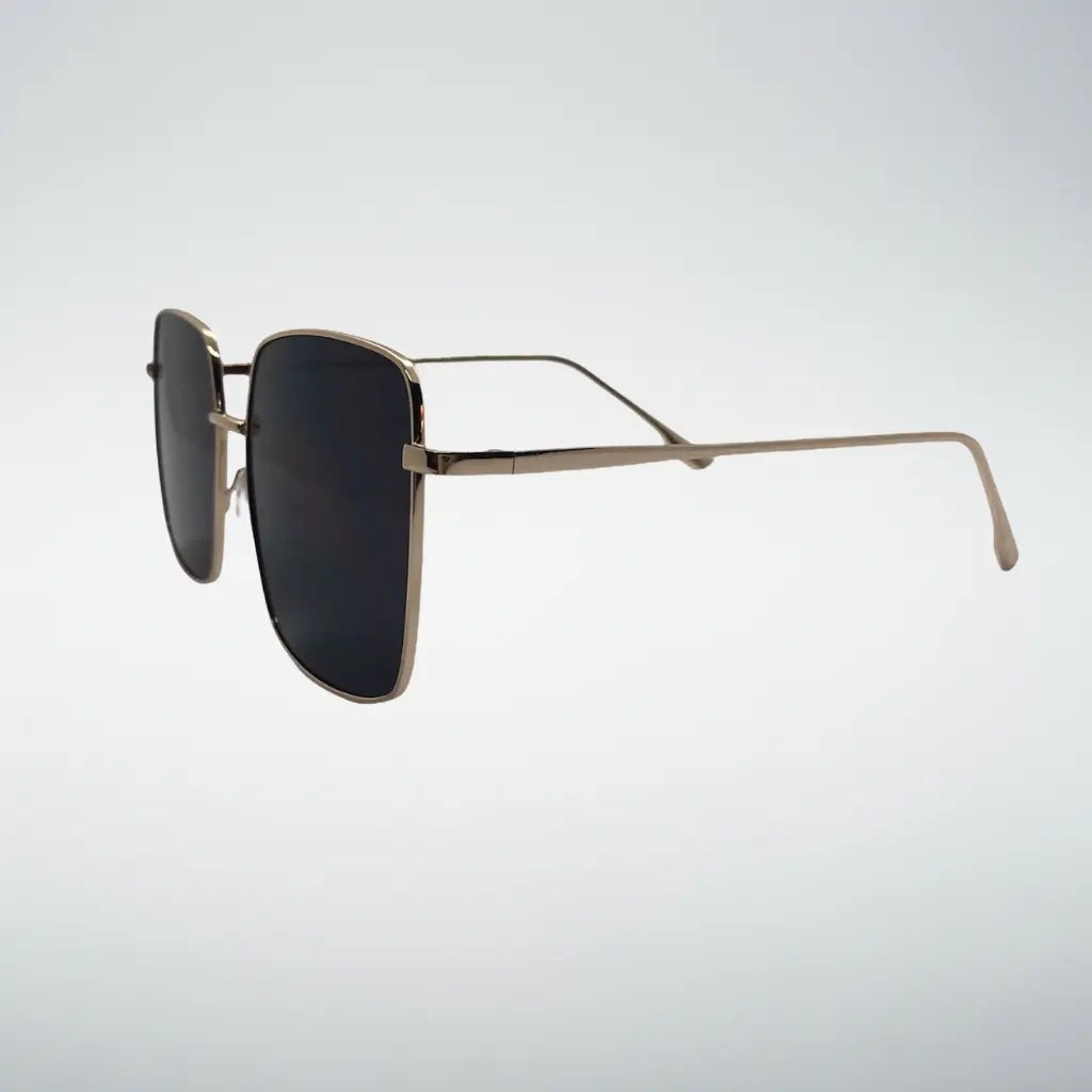 A pair of square aviator-style sunglasses with a thin gold metal frame and dark lenses, shown from a side profile against a light gray gradient background.