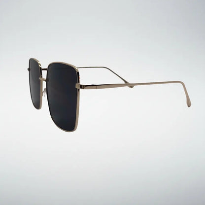 A pair of square aviator-style sunglasses with a thin gold metal frame and dark lenses, shown from a side profile against a light gray gradient background.