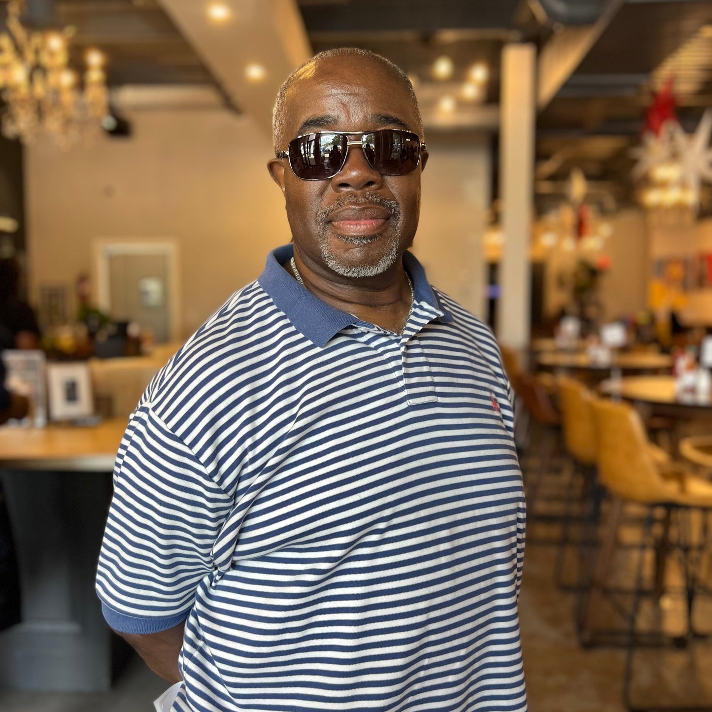 Man wearing sunglasses and a striped shirt in an indoor setting