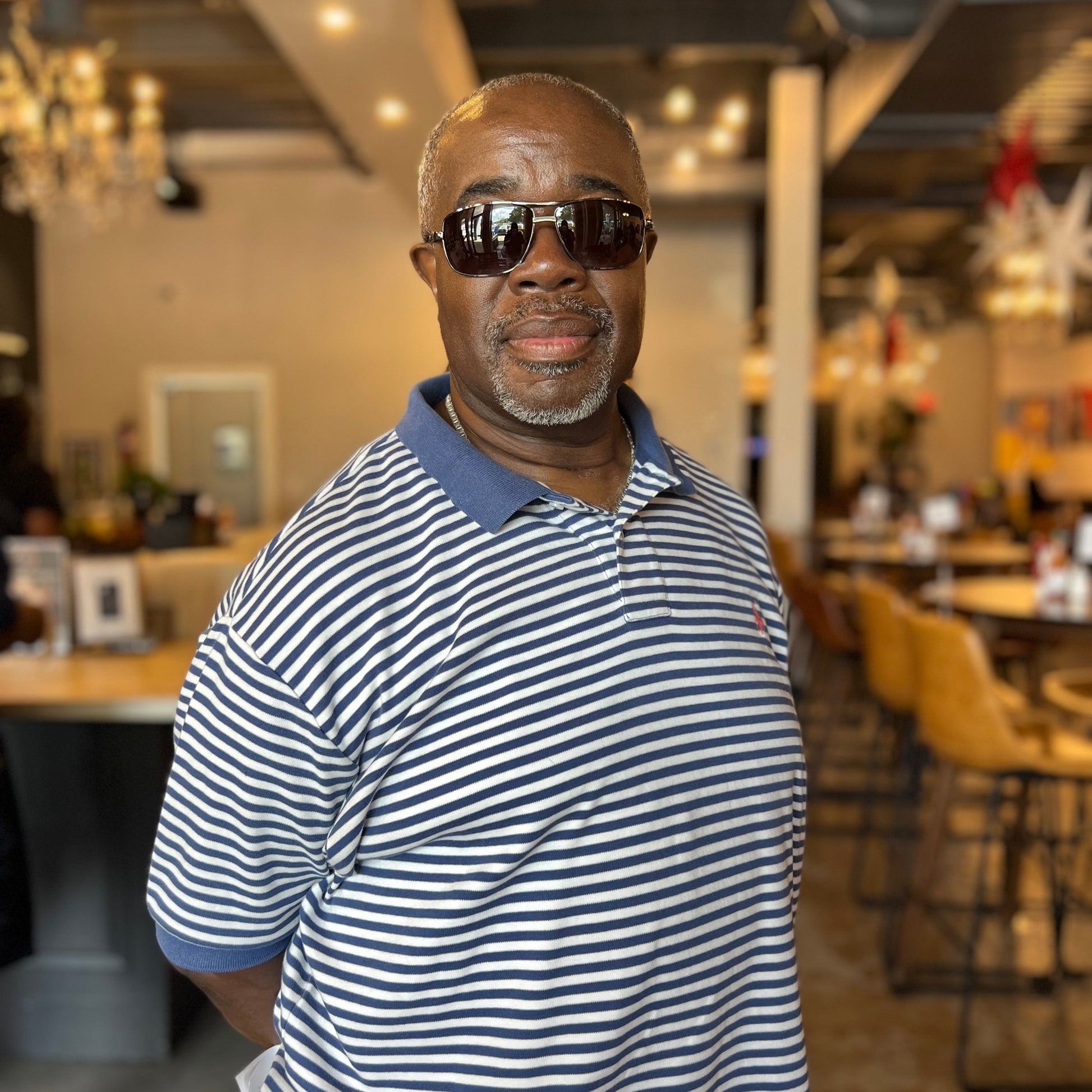 Man wearing sunglasses and a striped shirt in an indoor setting