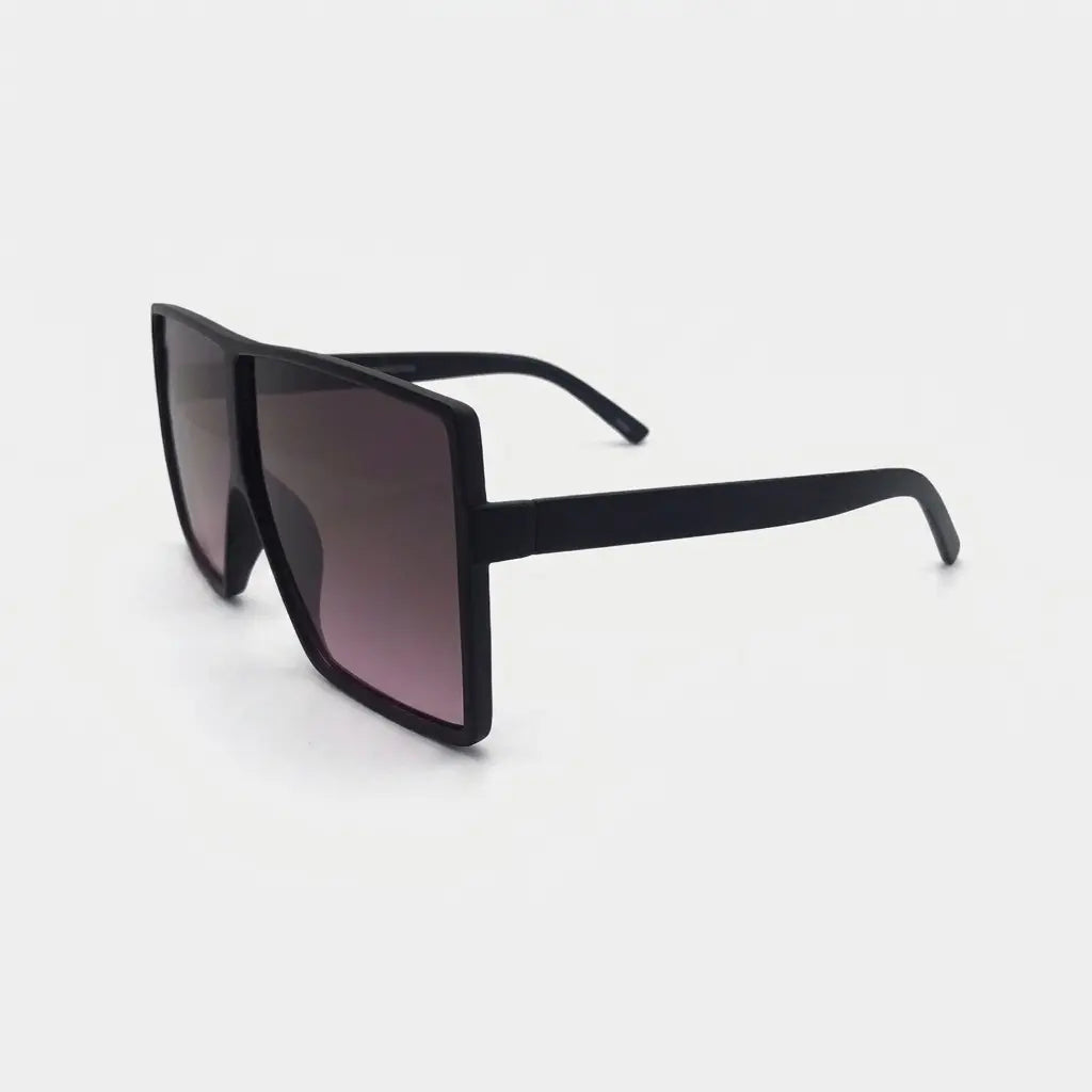 Side profile view of oversized square sunglasses with a black frame and pink gradient lenses displayed on a light gray background.