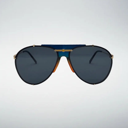 Aviator sunglasses with dark blue lenses, a black frame, gold metal accents, and a distinctive blue and orange gradient bridge, shown against a light gray background.