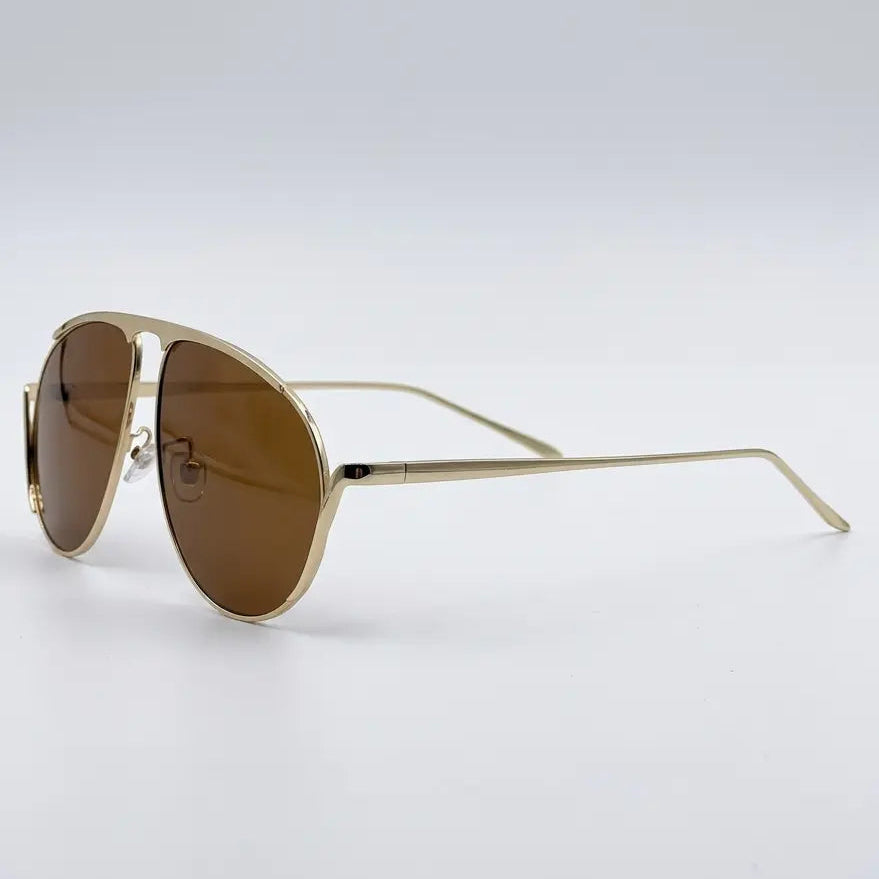 Gold-framed sunglasses with brown lenses on a light gray background