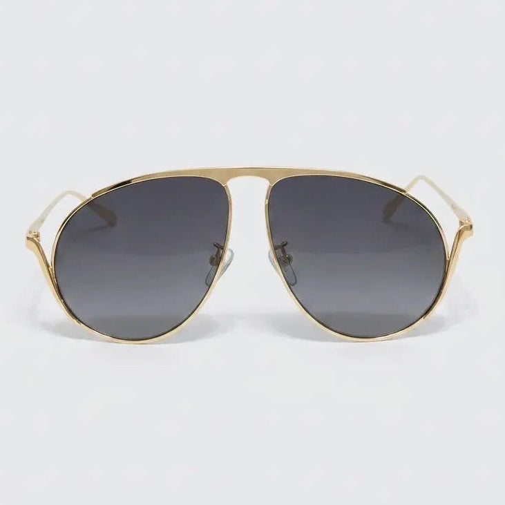 Gold-framed sunglasses with dark lenses on a light gray background
