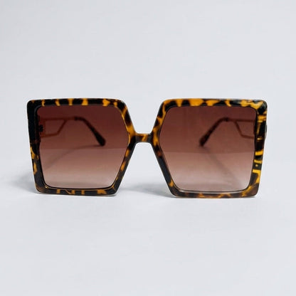 Sunglasses with tortoiseshell frame and brown gradient lenses on a light gray background